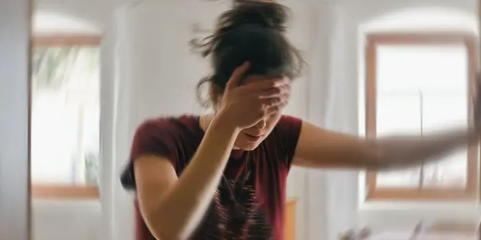 Person feeling dizzy and unsteady, holding onto a wall.